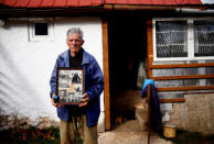 Mile Mladic, a cousin of the former Bosnian Serb military commander Ratko Mladic, poses for a photograph holding old family photos of Ratko Mladic and his family in front of his home, in the village where Ratko Mladic was born, Bozanovici, Bosnia and Herzegovina, November 9, 2017. REUTERS/Dado Ruvic