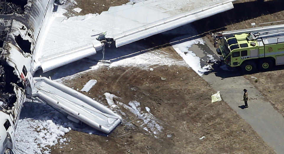 <p> FILE - In this July 6, 2013, aerial file photo, a firefighter stands by a tarpaulin sheet covering a body near the wreckage of the Asiana Flight 214 airplane after it crashed at the San Francisco International Airport in San Francisco, Saturday, July 6, 2013. On Friday, July 19, 2013, the San Mateo County Coroner's Office announced that 16-year-old victim, Ye Meng Yuan, survived the plane crash only to be run over and killed by a firefighters vehicle. (AP Photo/Marcio Jose Sanchez)</p>