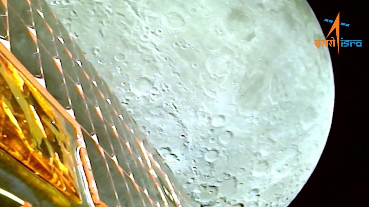  a shot of the moon from lunar orbit, with a spacecraft's golden solar array slanting across the moon's face in the foreground 