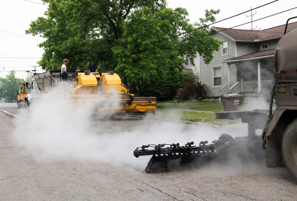 Road crews from Highway Maintenance & Construction, Romulus, perform street maintenance in June 2023 around the Adrian College campus. The road work being performed involves placing a layer of asphalt emulsion, a layer of fine aggregate, followed by another layer of asphalt emulsion.