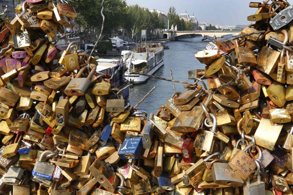 Padlocks clipped by lovers are seen on the fence of the Pont des Arts over the River Seine in Paris September 23, 2014. A city hall campaign to save the bridges of Paris from the weight of hundreds of thousands of brass "love locks" has not checked the ardour of droves of tourists, who continue to view the City of Light as the City of Love. Iron grills lining the bridges have since 2008 been increasingly covered by brass locks purporting to symbolize the unending love of visiting tourists. The city has begun to install thick plastic panels on the Pont des Arts, depriving lovers of the grillwork needed to affix their locks. (REUTERS/Jacky Naegelen)