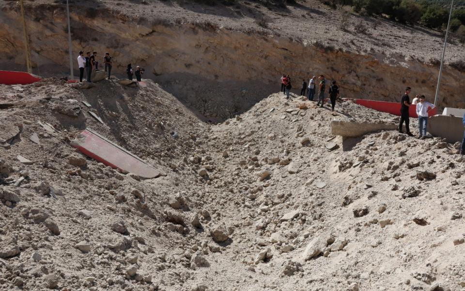 People stand at the site of an Israeli strike at Masnaa border crossing with Syria