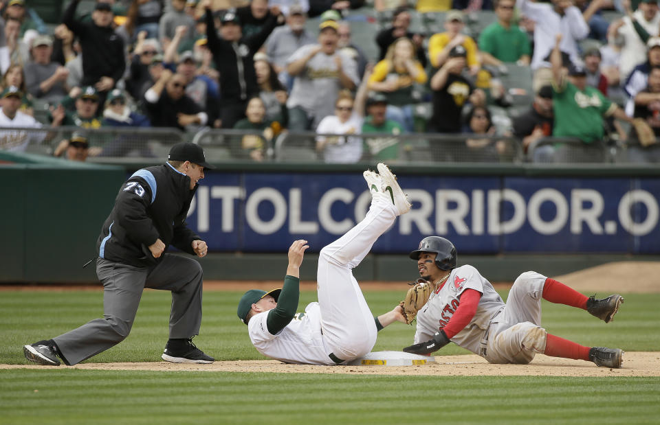 Boston Red Sox Mookie Betts, right, looks for the call from third base umpire Tripp Gibson after being tagged out by Oakland Athletics third baseman Matt Chapman in the ninth inning of a baseball game Thursday, April 4, 2019, in Oakland, Calif. Oakland won the game 7-3. Betts was thrown out at third base after the Red Sox's Andrew Benintendi singled to center field. (AP Photo/Eric Risberg)