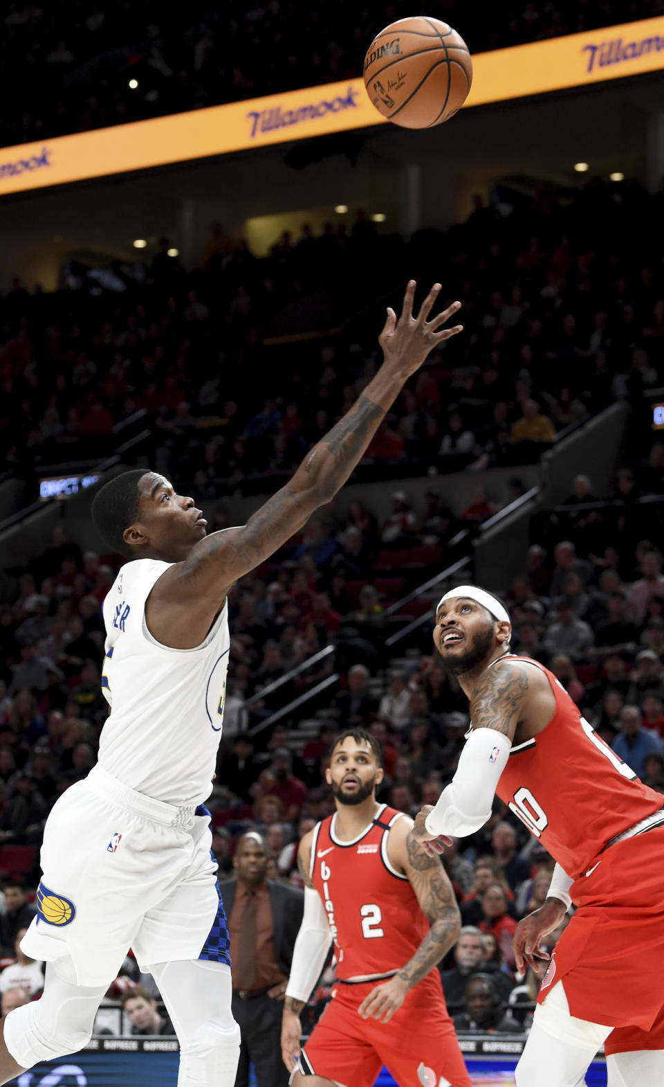 Indiana Pacers guard Edmond Sumner, left, drives to the basket on Portland Trail Blazers forward Carmelo Anthony, right, as guard Gary Trent Jr., center, looks on during the first half of an NBA basketball game in Portland, Ore., Sunday, Jan. 26, 2020. (AP Photo/Steve Dykes)