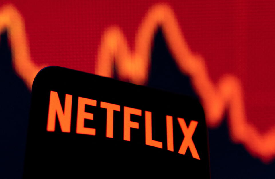 Netflix-logolla varustettu älypuhelin näkyy tässä 19. huhtikuuta 2022 otetussa kuvassa laskevan osakekaavion edessä. REUTERS/Dado Ruvic/Illustration