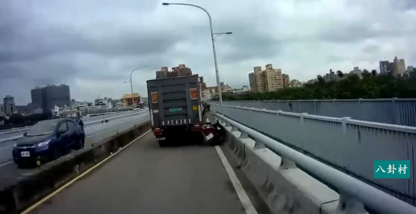 一名女騎士堅決鑽車縫，最終不幸遭撞摔倒在地。（圖／翻攝臉書／八卦2村 - 行車紀錄器影片上傳中心）