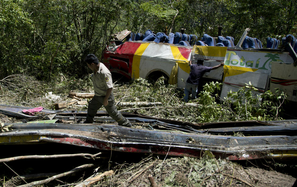 Un guardaparques camina en medio de los restos de un autobús que chocó de frente con otro vehículo y se precipitó a un barranco en Yolosa, Bolivia, el lunes 22 de abril de 2019. (AP Foto / Juan Karita)