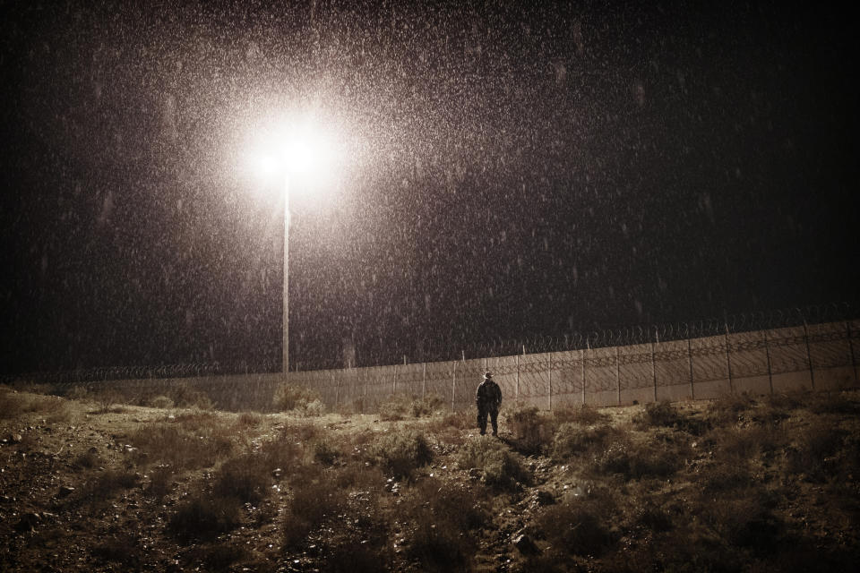 A U.S. Border Protection officer stands in heavy rain near the border fence between San Diego, Calif., and Tijuana, Mexico, on Jan. 1, 2019. (AP Photo/Daniel Ochoa de Olza)