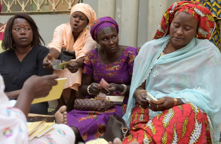 A family atmosphere reigns as different generations mix at the gathering. Sitting in chairs and on the ground, some hold babies as one by one, the women add their cash to the collection held in a dried gourd