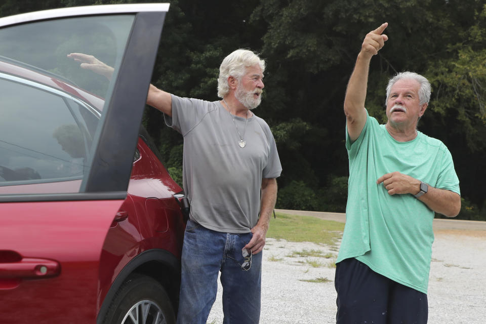 Jimmy Huddleston, left, and Daniel Alsup, right, discuss an airplane that crash-landed in a field near their Ripley, Miss. homes on Saturday, Sept. 3, 2022. Authorities say a man who stole a plane and flew it over Mississippi after threatening to crash it into a Walmart store faces charges of grand larceny and terroristic threats. Tupelo Police Chief John Quaka said Cory Wayne Patterson didn't have a pilot's license but had some flight instruction and was an employee of Tupelo Aviation. (AP Photo/Nikki Boertman)