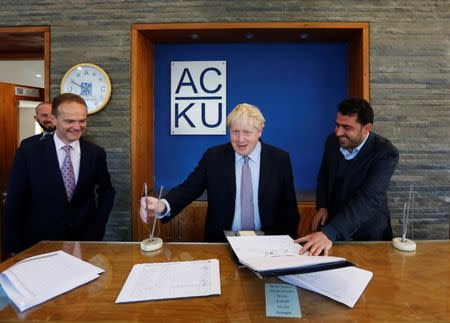 Britain's Foreign Secretary Boris Johnson (C) signs next to British ambassador to Afghanistan Dominic Jermey (L) during his visit the Afghanistan Centre at Kabul University (ACKU) in Kabul, Afghanistan November 26, 2016. REUTERS/Mohammad Ismail