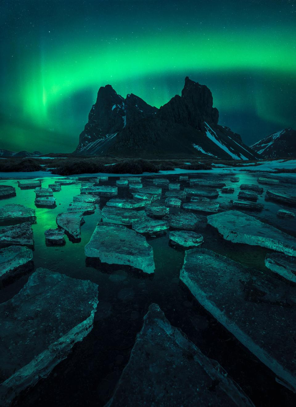 auroras above jagged landscape bathed in green