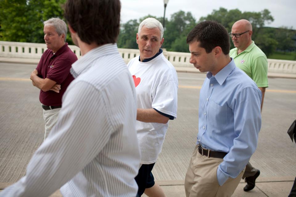In this July 3, 2013, file photo, then-Indiana Gov. Mike Pence, center, talks with South Bend mayor Pete Buttigieg, right, as they cross the Jefferson Boulevard bridge during a fitness walk along the St. Joseph River in downtown South Bend, Ind.