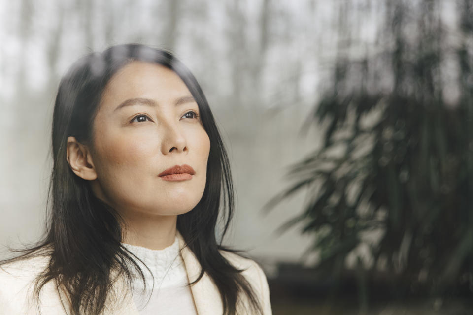 Thoughtful mid adult businesswoman looking through window at office