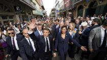 French President Emmanuel Macron waves to the crowd as he walks down Royal Street with New Orleans Mayor Latoya Cantrell in the French Quarter of New Orleans, Friday, Dec. 2, 2022. Behind Cantrell are former Mayor Mitch Landrieu and his wife, Cheryl Quirk. (AP Photo/Gerald Herbert)