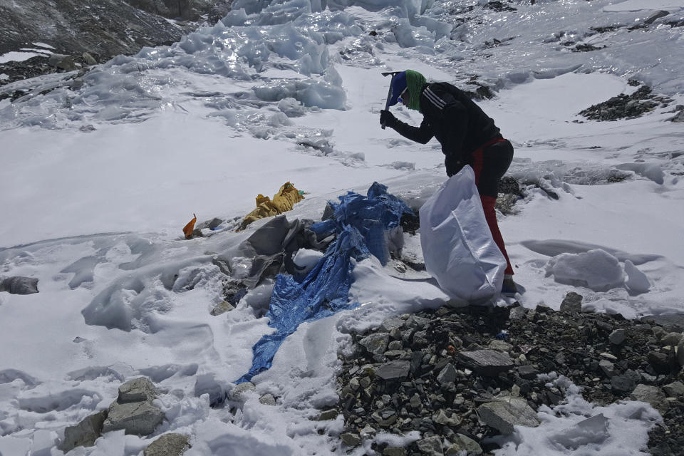 This image provided by the Peak Promotion shows a member of the Nepal government-funded team using a spade to remove frozen trash en route the Mount Everest, Nepal, Tuesday, April 27, 2021. In the seven decades since Mount Everest was first conquered, thousands of climbers have scaled the peak, and many have left behind more than just their footprints. Tons of trash and several bodies remain on the icy slopes of the world's highest mountain. (Peak Promotion via AP)