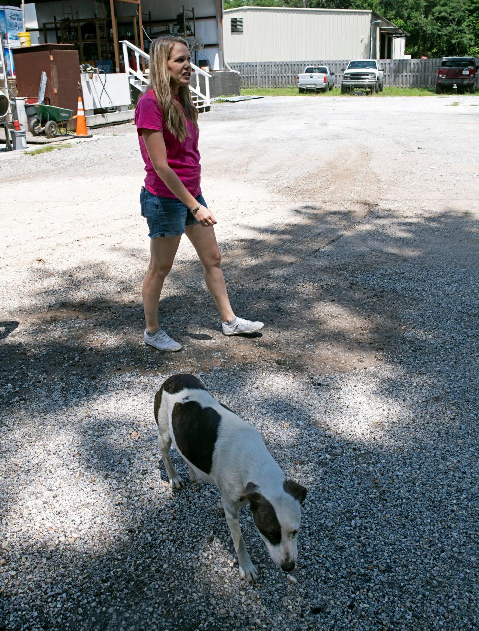 Chelsey Fowler, vice president of Peterson Precision Painting, walks company property accompanied by a stray dog from the homeless camp behind the family-owned business on Monday, May 22, 2023. Business owners around the Beggs Lane homeless camp have voiced frustration about the county's lack of concern and unwillingness to address the issue. 