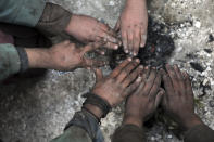 Internally displaced boys warm themselves near a fire outside of their temporary home in the city of Kabul, Afghanistan, Wednesday, Dec. 30, 2020. Save the Children has warned that more than 300,000 Afghan children face freezing winter conditions that could lead to illness, in the worst cases death, without proper winter clothing and heating. (AP Photo/Rahmat Gul)