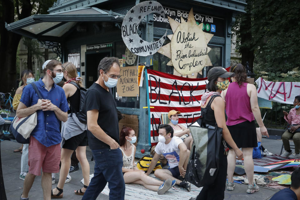 Protesters rest on the pavement outside a subway station entrance at an encampment outside City Hall, Friday, June 26, 2020, in New York. (AP Photo/John Minchillo)