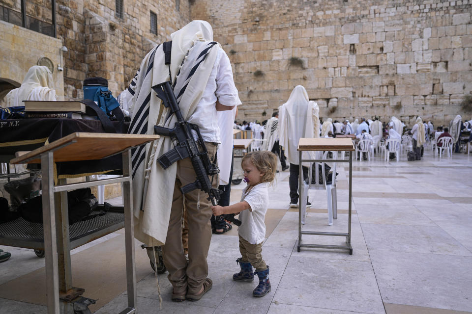 An off-duty member of Israel's security forces joins worshippers at the Western Wall, the holiest site where Jews can pray, in the Old City of Jerusalem, Tuesday, Nov. 14, 2023. Tens of thousands of Israeli reservists have been called up for action for the war against Hamas, while other security personnel have begun to carry weapons in public, following the Islamic militant group's deadly cross-border attack on Oct. 7. (AP Photo/Ohad Zwigenberg)