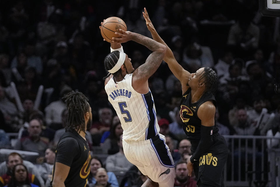 Orlando Magic forward Paolo Banchero (5) shoots as Cleveland Cavaliers forward Isaac Okoro, right, defends in the second half of an NBA basketball game, Wednesday, Dec. 6, 2023, in Cleveland. (AP Photo/Sue Ogrocki)