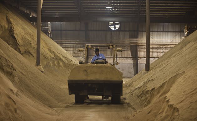 A worker drives a tractor past mounds of dried and crushed Menhaden fish, to be used as animal feed supplements, at the Omega Protein processing plant in Reedville, Virginia, on June 23, 2015. 
