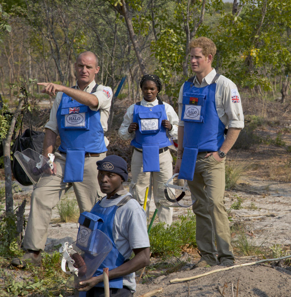 In this handout photo made available by the HALO Trust on Saturday, Aug. 17, 2013, Gerhard Zank, left, deminer Mateus Canhanga, foreground, section leader Maria Ilda da Piedade, center, and Britain's Prince Harry, discuss clearance techniques. Harry returned from Angola, where he visited a landmine clearance charity championed by his late mother, Princess Diana. The HALO Trust charity said Saturday the 28-year-old prince visited the Angolan town of Cuito Cuanavale, which saw heavy fighting during the southern African nation’s 1975-2002 civil war. The group said Harry toured minefields and met beneficiaries of the group’s work. (AP Photo/HALO Trust)