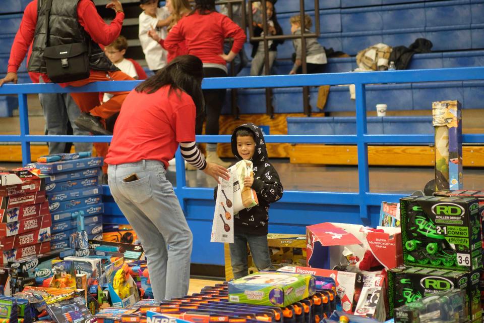 A volunteer helps an excited child Saturday at the 10th annual Northside Toy Drive, held at the Palo Duro High School Gym in Amarillo.