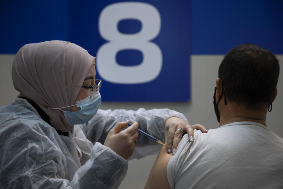 An Israeli man receives his second Pfizer-BioNTech COVID-19 vaccine from a medical professional at a vaccination center set up on a mall parking lot in Givataim, Israel, during a nationwide lockdown to curb the spread of the virus, Wednesday, Jan. 20, 2021. (AP Photo/Oded Balilty)