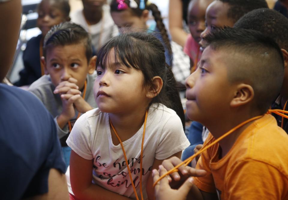 Students Jesuacd Torres Castellon, left, Maryori Molina Quinonez, middle, and Roberto Gomez Ruiz, right, listen to a story being read to them in the library at Valencia Newcomer School during class Thursday, Oct. 17, 2019, in Phoenix. Children from around the world are learning the English skills and American classroom customs they need to succeed at so-called newcomer schools. Valencia Newcomer School in Phoenix is among a handful of such public schools in the United States dedicated exclusively to helping some of the thousands of children who arrive in the country annually. (AP Photo/Ross D. Franklin)