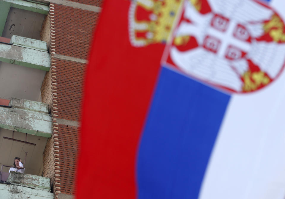 A woman standing on a balcony listens Serbian President Aleksandar Vucic during a rally in the northern, Serb-dominated part of Mitrovica, Kosovo, Sunday, Sept. 9, 2018. NATO-led peacekeepers in Kosovo say the safety of Serbia President Aleksandar Vucic during a visit to Kosovo isn't threatened despite roadblocks that prevented his visit to a central Serb-populated village. (AP Photo/Darko Vojinovic)