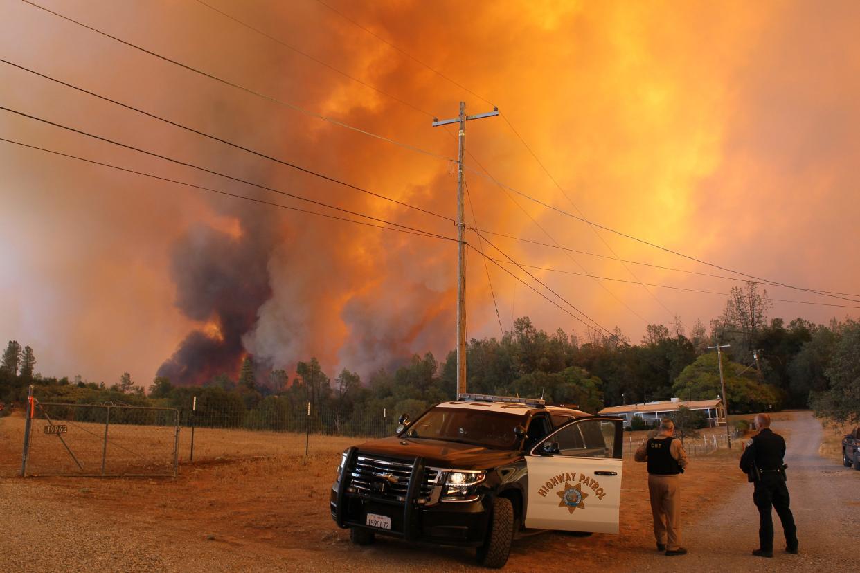 File photo - California Highway Patrol and Redding police officers watch as the Fawn Fire picks up in a ravine near Old Oregon Road near Redding early Thursday afternoon, Sept. 23, 2021.