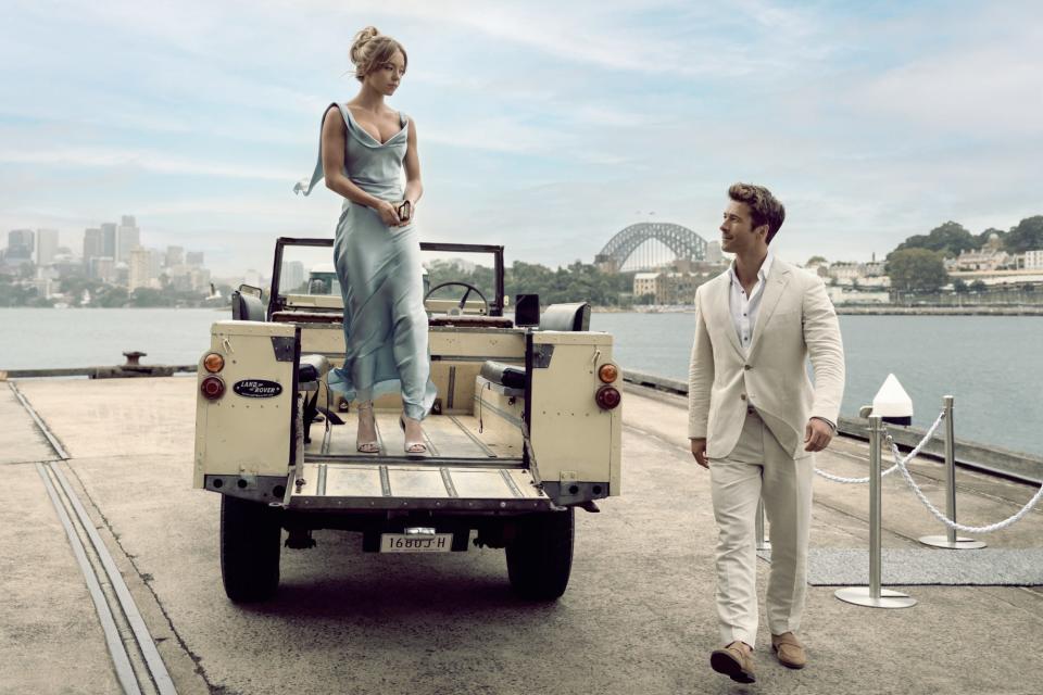 Sydney Sweeney standing in a truck next to Glen Powell walking