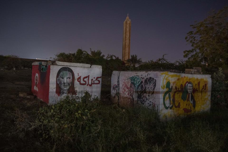 This Jan. 12, 2020 photo, shows graffiti and Arabic that reads, "Kandaka," referring to a queen of the old Nubian civilization, left, and "the blood of the martyr hasn't disappeared," backdropped by a mosque where many women were beaten and raped inside the compound during the June 3, 2019 paramilitary crackdown on a protest camp in Khartoum, Sudan. Soldiers from the Rapid Support Forces broke in, beating people, several women said. They told similar stories of RSF fighters corralling up fleeing protesters, beating them, sexually molesting the women and gang-raping some. (AP Photo/Nariman El-Mofty)