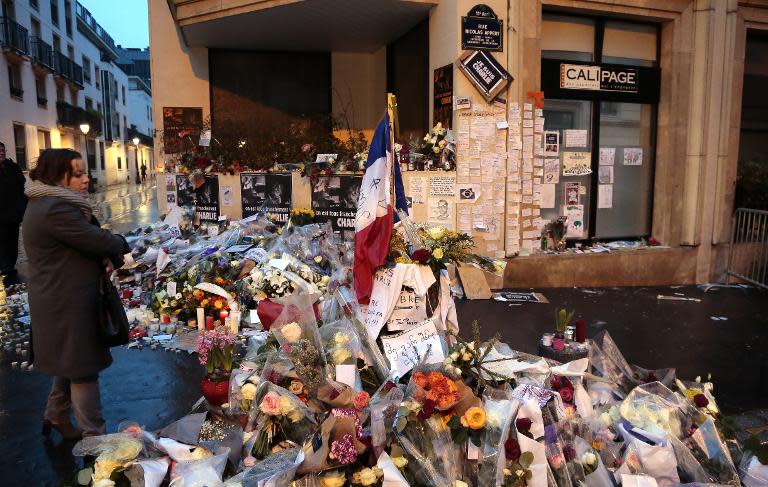 A woman looks at floral tributes left outside the Charlie Hebdo magazine offices in Paris early on January 9, 2015