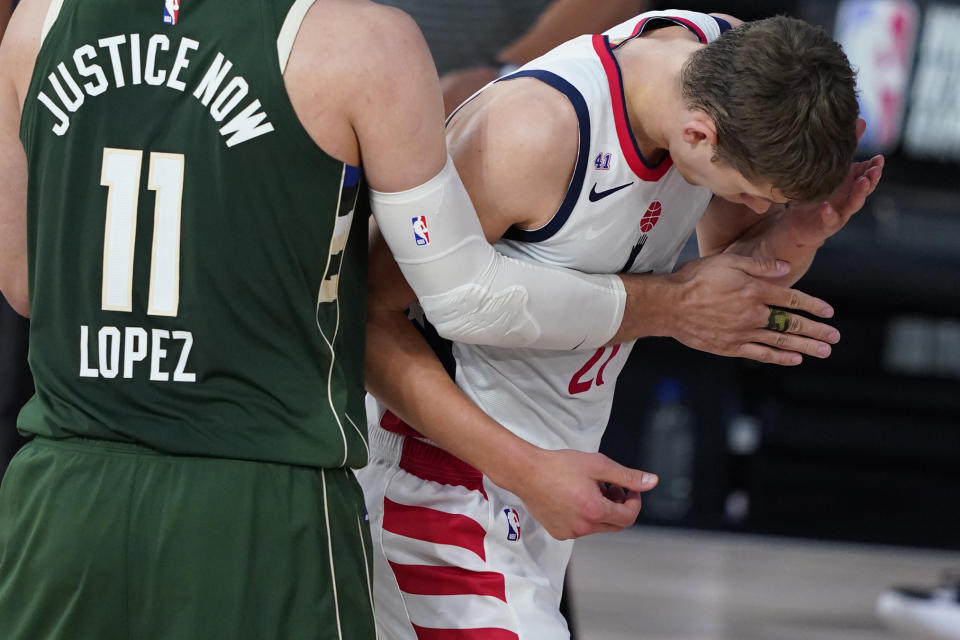 Washington Wizards' Moritz Wagner (21) grabs his face after getting head butted by Milwaukee Bucks' Giannis Antetokounmpo during the first half of an NBA basketball game, Tuesday, Aug. 11, 2020, in Lake Buena Vista, Fla. Antetokounmpo was ejected from the game. (AP Photo/Ashley Landis, Pool)