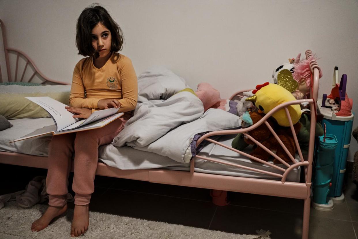 A girl sitting in bed reads a book