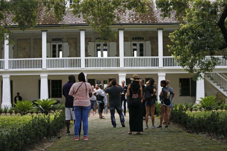 In this July 14, 2017 file photo, visitors walk outside the main plantation house at the Whitney Plantation in Edgard, La. The Whitney, which documents slavery at a pre-Civil War plantation near New Orleans, draws tens of thousands of visitors annually and is known for discussing topics that other tourist plantations ignore. Yet even its entry in the National Register, completed in 1992 before the current owner purchased it, doesn't mention the slaves who toiled there. (AP Photo/Gerald Herbert, File)