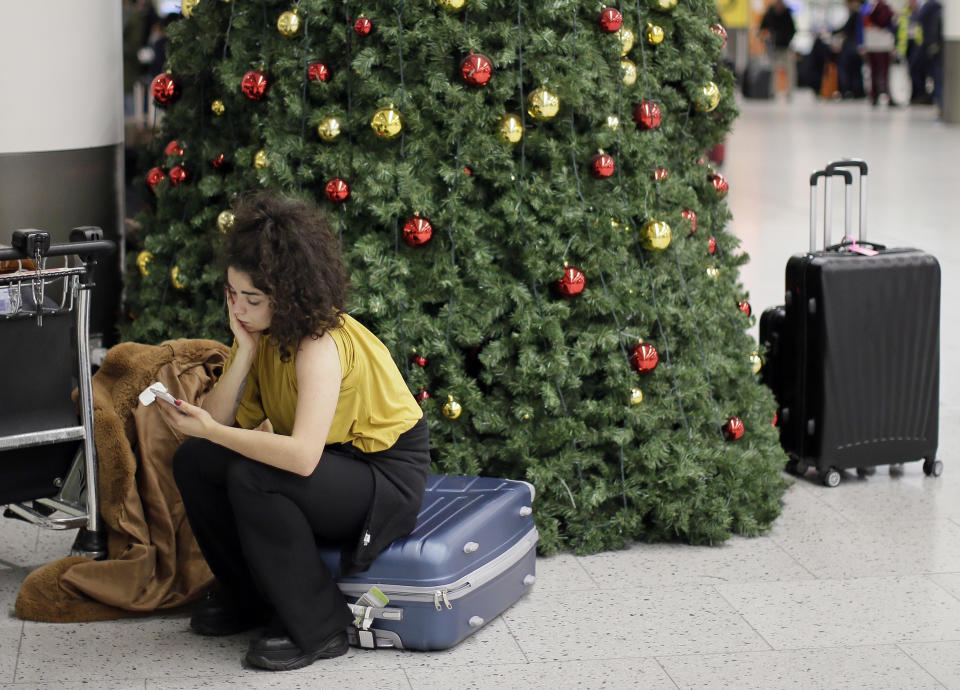 A woman waits in the departures area at Gatwick airport, near London, as the airport remains closed with incoming flights delayed or diverted to other airports, after drones were spotted over the airfield last night and this morning, Thursday, Dec. 20, 2018. London's Gatwick Airport remained shut during the busy holiday period Thursday while police and airport officials investigate reports that drones were flying in the area of the airfield. (AP Photo/Tim Ireland)