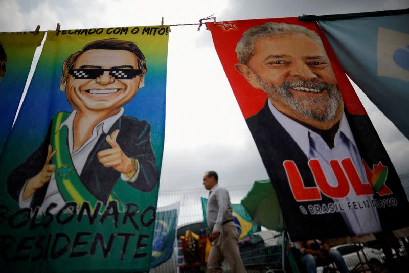 FILE PHOTO: A man walks past presidential campaign materials depicting Brazil's former President Luiz Inacio Lula da Silva and and President Jair Bolsonaro in Brasilia