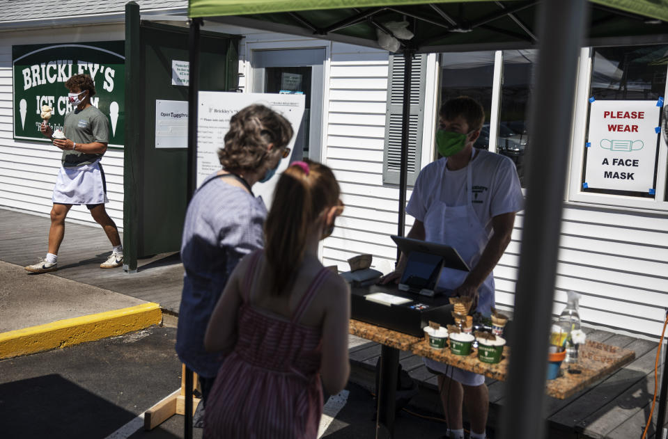 Employees serve customers with masks at a Brickley's Ice Cream shop, one of two stores, in Narragansett, R.I., Wednesday, July 29, 2020. The other nearby location closed when teenage workers were harassed by customers who refused to wear a mask or socially distance. Disputes over masks and mask mandates are playing out at businesses, on public transportation and in public places across America and other nations. (AP Photo/David Goldman)