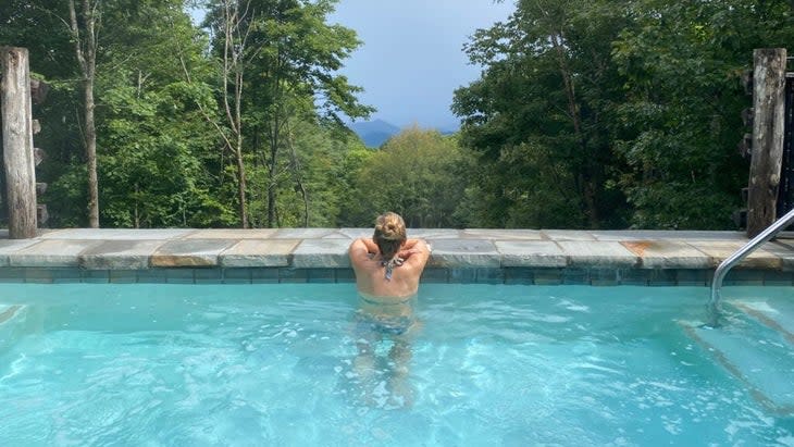 A woman in the hotel pool, staring out at the Appalachians in the distance