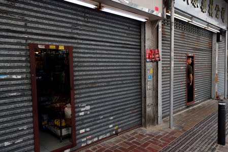 FILE PHOTO: A shopkeeper looks out from a closes door as protesters attend a march at an anti-parallel trading at Sheung Shui, a border town in Hong Kong