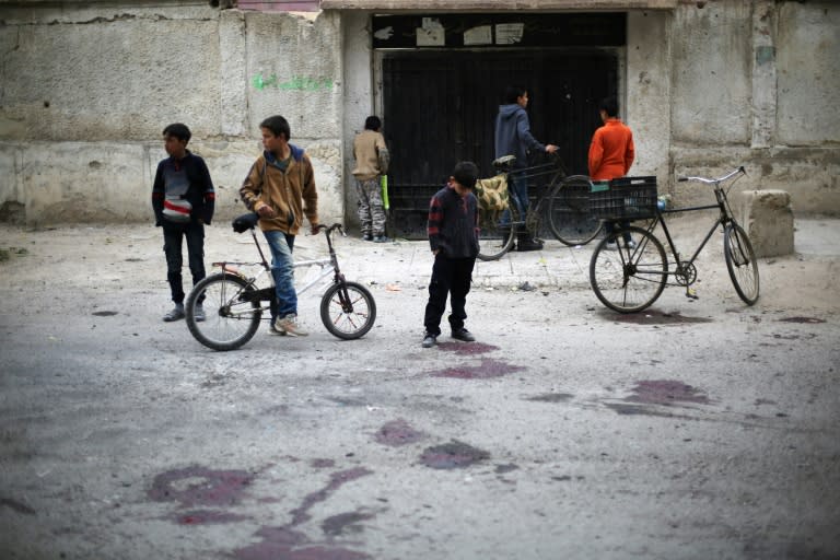 Syrian children stand at the blood stained scene of a reported government shelling that killed schoolchildren in the rebel-held besieged town of Jisreen, east of the capital Damascus, on October 31, 2017