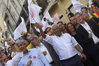 Portuguese Prime Minister and Socialist Party leader Antonio Costa, center, holds up a rose during an election campaign action in downtown Lisbon Friday, Oct. 4, 2019. Portugal will hold a general election on Oct. 6 in which voters will choose members of the next Portuguese parliament. The ruling Socialist Party hopes an economic recovery during its four years of governing will persuade voters to return the party to power. (AP Photo/Armando Franca)