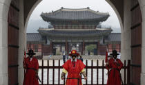 Workers wearing face masks stand during a re-enactment of the changing of the Royal Guard in front of the Gwanghwamun, the main gate of the 14th-century Gyeongbok Palace, and one of South Korea's well-known landmarks, in Seoul, South Korea, Saturday, Aug. 15, 2020. (AP Photo/Lee Jin-man)