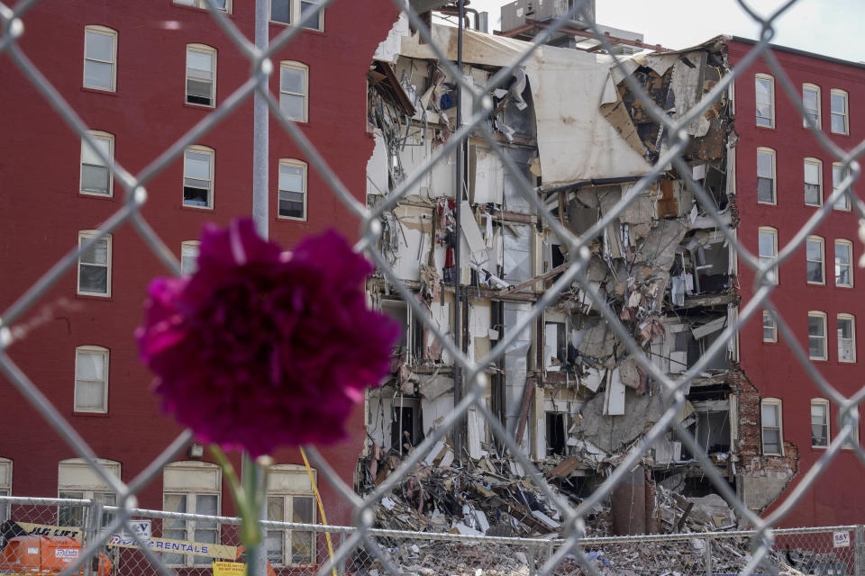 A flower hangs from a fence at the where on Sunday an apartment building partially collapsed in Davenport, Iowa, Wednesday, May 31, 2023. Five residents of a six-story apartment building that partially collapsed in eastern Iowa remained unaccounted for Tuesday, and authorities feared at least two of them might be stuck inside rubble that was too dangerous to search. (AP Photo/Erin Hooley)