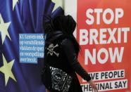 A woman walks past a billboard depicting a photo of a placard reading "Stop Brexit Now" at Central railway station in Brussels