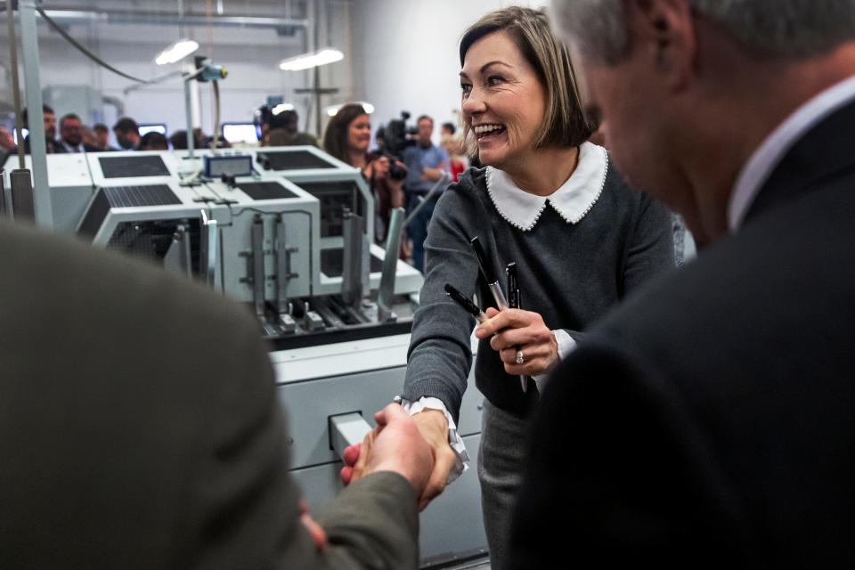 Gov. Kim Reynolds hands out pens to legislators and other supporters after signing the 3.9% flat tax into law, on Tuesday, March 1, 2022, at LBS, a bookbinding and packaging company in Des Moines.