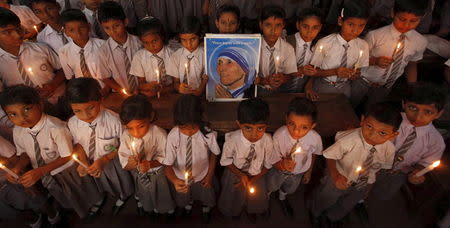 School children take part in a candlelight prayer ceremony as they hold a portrait of Mother Teresa on the occasion of her 101st birth anniversary celebrations in Kolkata, India, in this August 26, 2011 file photo. REUTERS/Rupak De Chowdhuri/Files